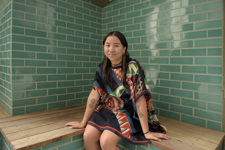 Female student, sitting on wooden bench surrounded by green tiles