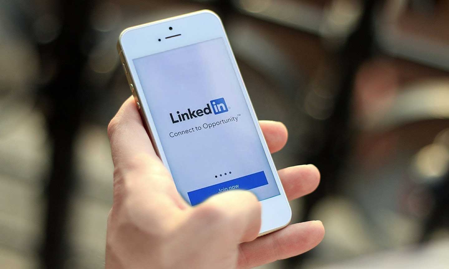 A hand holding a phone with the LinkedIn app open.