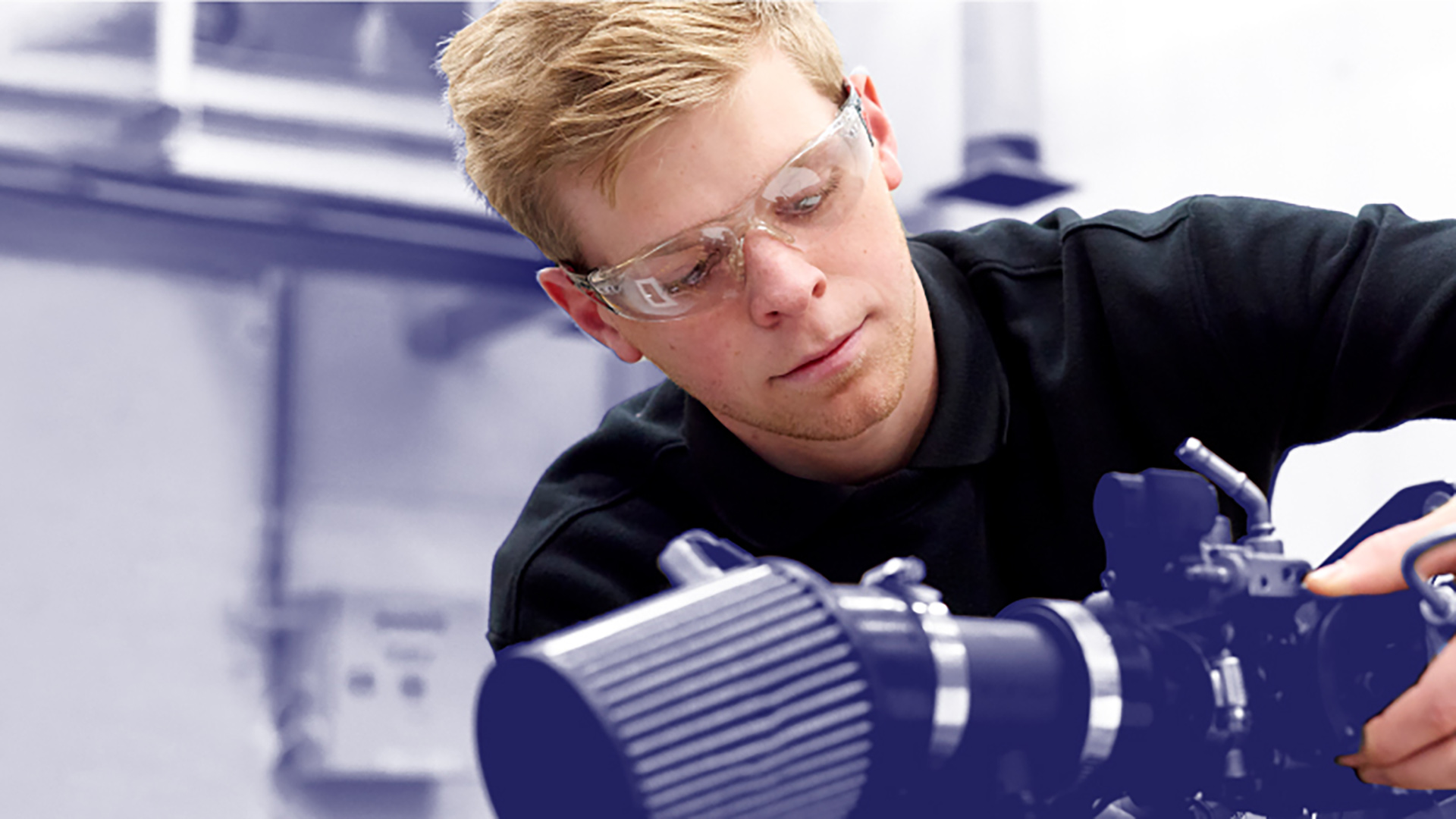 male student using science equipment wearing safely glasses