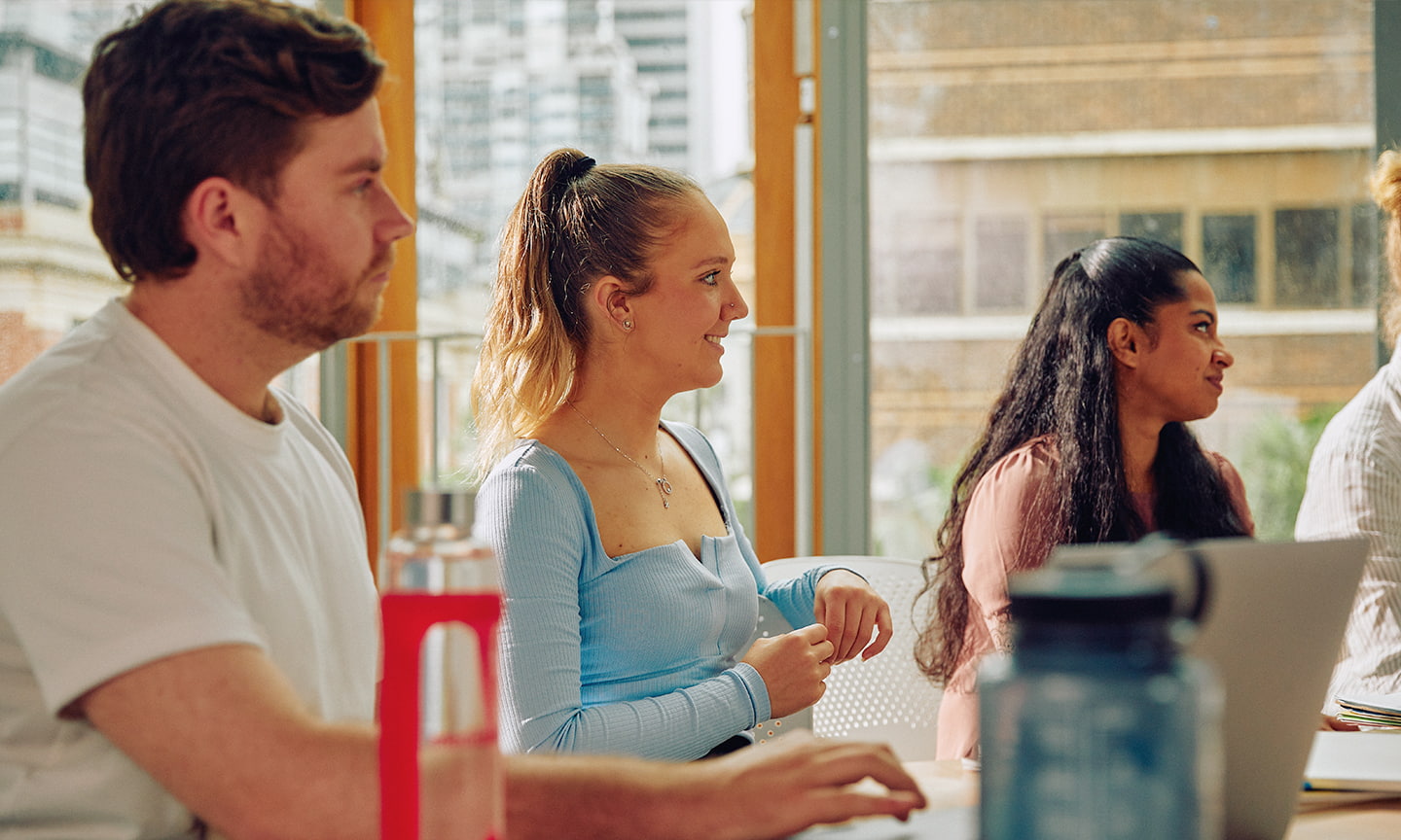 Three RMIT students sitting at a table looking out of frame at a presenter