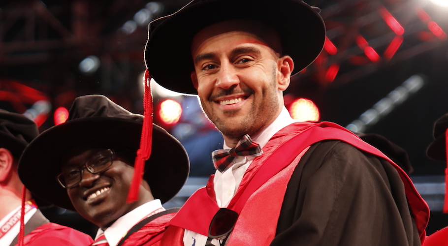 PhD graduate smiles at camera at the graduation ceremony.