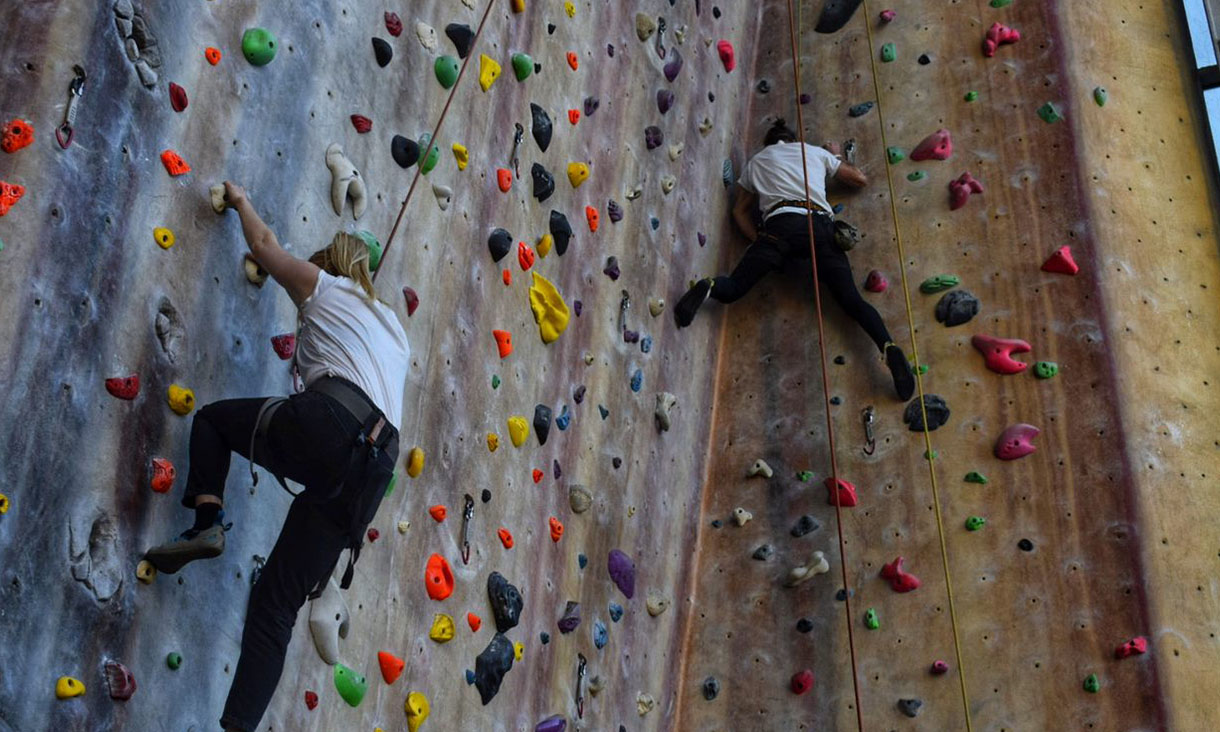 Two people climbing an indoor rock climbing wall