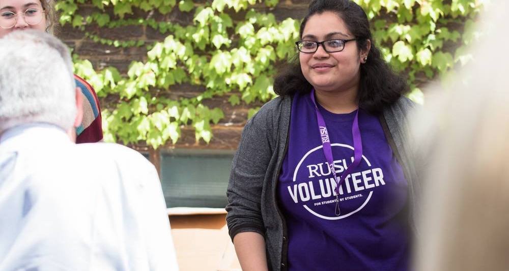 A RUSU volunteer smiles at others on campus.