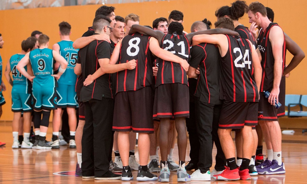 RMIT basketballers huddle in a group on a court.