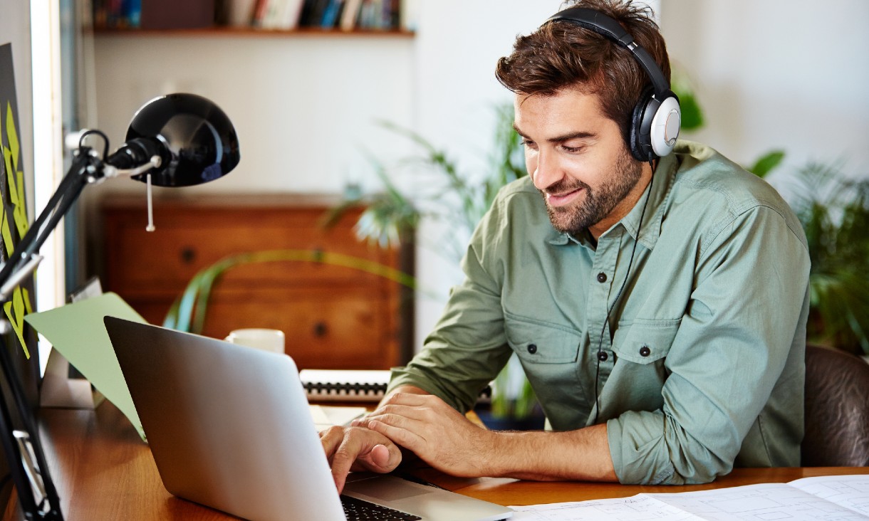 Man wearing headphones, working on a laptop