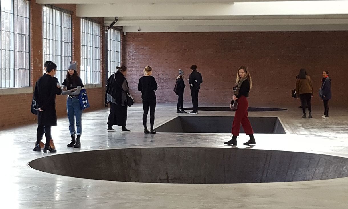 Huge geometric holes cut into the floor of a gallery space